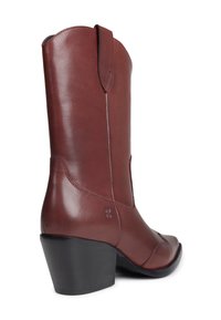 Bota de vaquero de cuero marrón con un tacón negro apilado de altura media, tirador y punta afilada, mostrada desde un ángulo posterior.