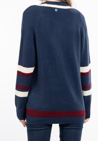 Marinblå stickad tröja med vita och röda ränder på ärmarna, rund hals och en knappdetalj bak. Mjukt material och avslappnad passform.