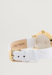 Ceas cu bratara din piele alba, avand un carcasă rotundă de culoare aurie, o bratara texturată și un design minimalist cu un capac din sticlă transparentă.