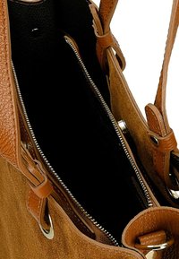 Brązowa torebka z zamszu o teksturowanym wykończeniu, z zamkiem błyskawicznym i skórzanymi akcentami. Wnętrze jest czarne, oferujące dużo przestrzeni i detali.