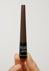 Eyeliner liquide Revlon Colorstay dans un container noir et marron de 2,5 mL, avec un applicateur en plastique effilé et un étiquetage clair.