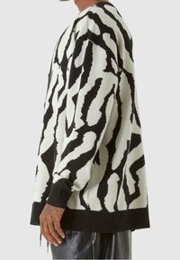 Svart- och vittmönstrad stickad tröja med avslappnad passform. Har långa ärmar, ribbade ärmslut och rundad halsringning.