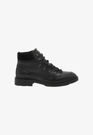 Bota negra de cuero con cordones hasta el tobillo, con cuello acolchado, ojales metálicos y suela con textura antideslizante, mostrada en perfil lateral sobre fondo blanco.