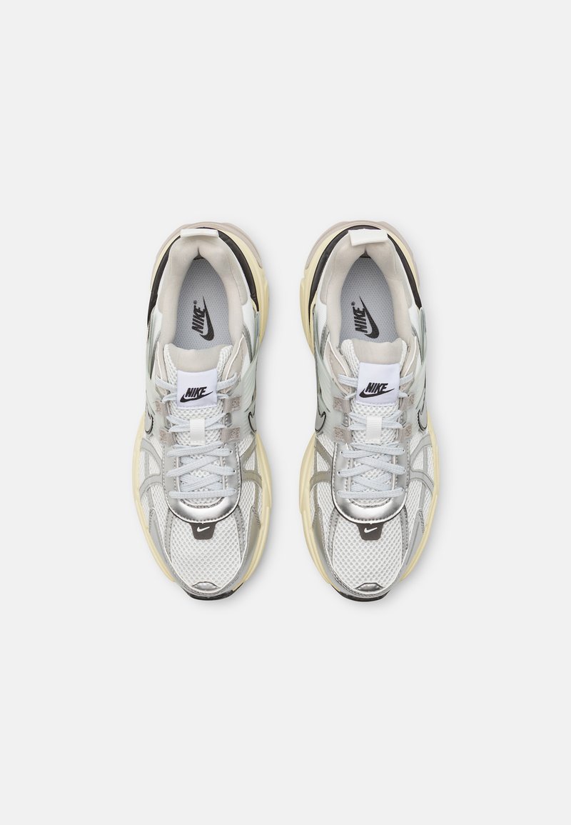 Zapatillas de deporte con malla, cuero y materiales sintéticos. Predominantemente plateadas con acentos negros, presentan una suela acolchada y un diseño con cordones.