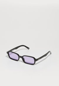 Gafas de sol rectangulares negras con lentes tintados de púrpura. Hechas de plástico, con un acabado brillante y patas delgadas negras con acentos dorados.