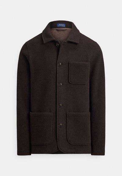 Casaco de lã castanho escuro com fecho de botões, gola pontiaguda e dois grandes bolsos frontais. Apresenta um bolso no peito e textura suave.