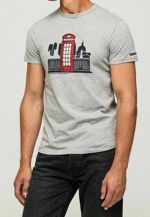T-shirt gris en coton avec un motif de cabine téléphonique rouge, sur un design de skyline urbaine. Manches courtes, encolure ronde, coupe décontractée.