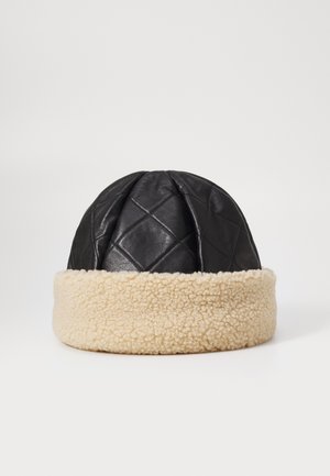 Chapeau en cuir noir matelassé avec un revers en fausse fourrure crème, présentant une forme arrondie et des détails cousus sur le dessus.
