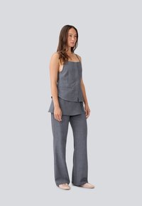 Ensemble deux pièces gris sur mesure comprenant un débardeur ajusté avec des bretelles fines et un pantalon à jambes larges. Une texture subtile et des lignes épurées sont visibles.