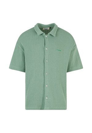 Chemise à manches courtes, côtelée, de couleur vert clair, avec un devant boutonné et un logo brodé discret de la même teinte. Tissu doux et texturé.