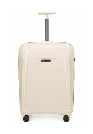 Valise cabine rigide beige avec quatre roues noires pivotantes et une poignée télescopique étendue avec une prise en forme de T.