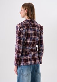 Blazer van een wolmix met een pied-de-poulemotief in bordeauxrood, blauw en crème; met reverkraag en lange mouwen; getailleerde pasvorm. Spijkerrok zichtbaar.