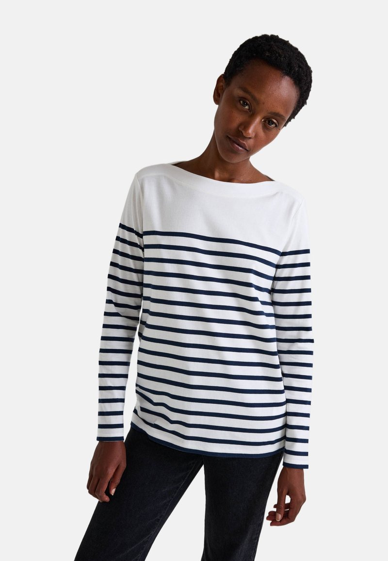 Chemise à manches longues en coton blanc avec des rayures horizontales navy. Présente un col bateau et une coupe décontractée. La texture est lisse et douce.