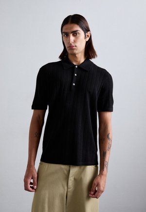 Svart stickad polo-shirt med krage, treknappslucka, korta ärmar och vertikal ribbstruktur.
