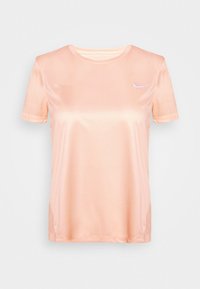 Perzikkleurig T-shirt met korte mouwen, gemaakt van gladde stof. Heeft een ronde hals en een klein wit logo op de linkerborst.