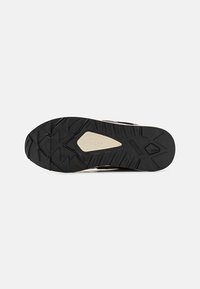 Black rubber shoe sole with textured tread pattern. Features light-colored accents and a robust design for traction on various surfaces.