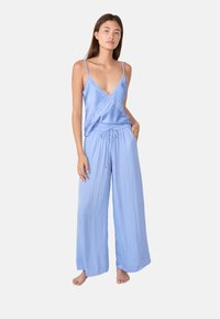 Lichtblauwe nachtmode set met een mouwloze top met kantafwerking en wijde broek met een verstelbare trekkoord taille. Zachte textuur.