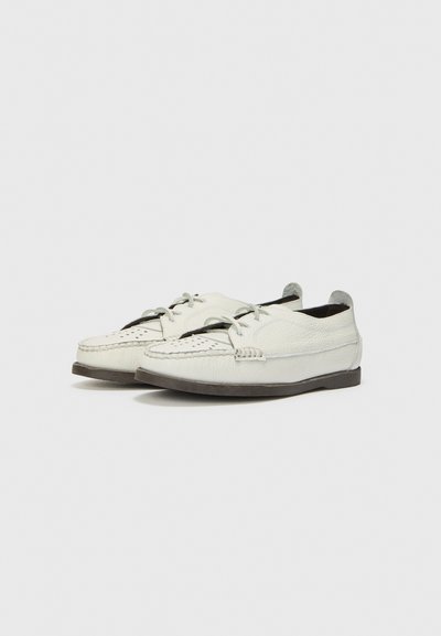 Scarpe da barca in pelle bianca con punta tonda, cuciture decorative e chiusura con lacci. Presentano una finitura testurizzata e una suola esterna marrone scuro.