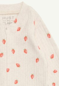 Weißes geripptes Baumwollkleidungsstück mit einem Reißverschluss, verziert mit einem sich wiederholenden Erdbeermuster in Pink und Grün. Das Etikett trägt die Aufschrift "HUST und CLAIRE."