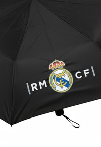 Zwarte paraplu met het logo van Real Madrid CF in blauw en wit, met een gouden kroon boven het embleem. Tekst luidt "|RM CF|."