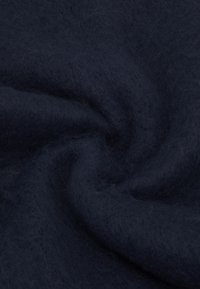 Tissu bleu marine foncé avec une texture douce et duveteuse, présentant un motif légèrement ondulé et de la profondeur grâce à ses couches et plis.