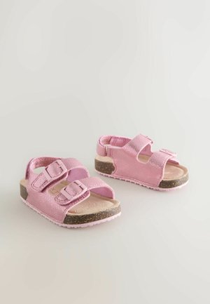 Sandales roses avec deux brides réglables et boucles, en matériau brillant, dotées d'une semelle intérieure texturée et d'une semelle extérieure marron texturée.