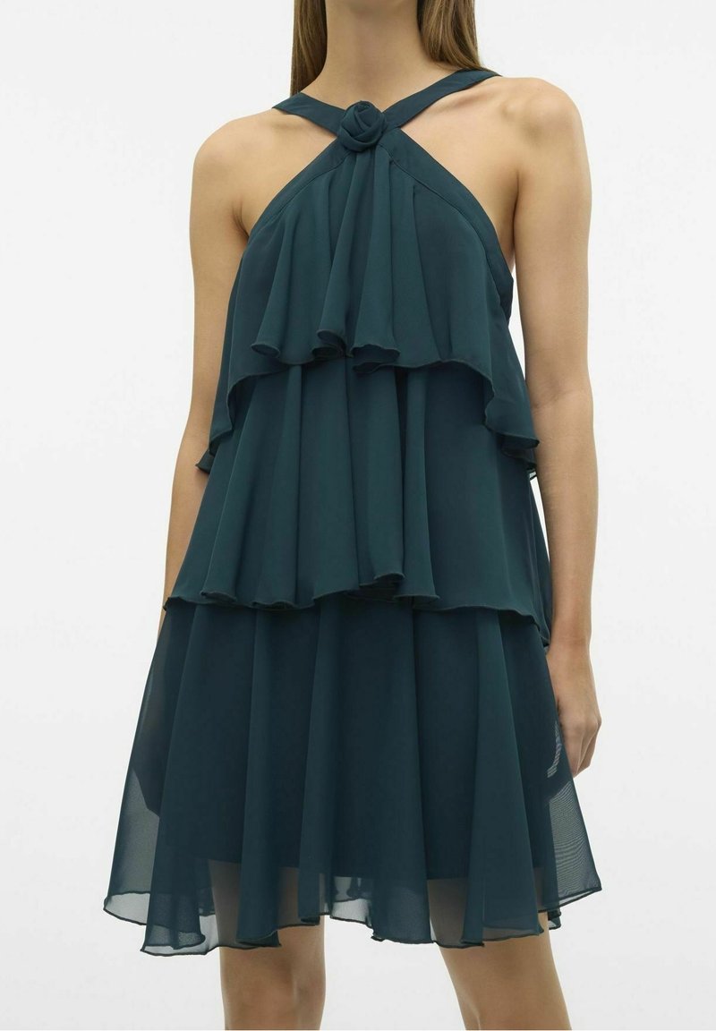 Robe en chiffon bleu sarcelle avec un col licou, des volants superposés et un détail noué au niveau de l'encolure.