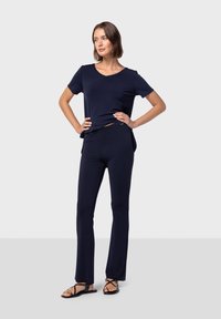 Marinblå mjuk tyg t-shirt med V-hals, matchad med skräddarsydda byxor och platta sandaler, som visar en avslappnad passform och enkel design.