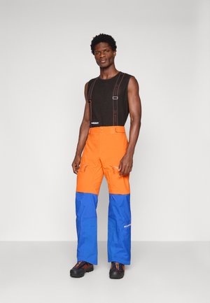 Helle orange Hosen mit blauen unteren Abschnitten und Reißverschlusstaschen. Verfügt über verstellbare Träger und einen robusten Bund. Glatte Stofftextur.