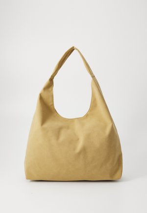 Sac fourre-tout en similicuir jaune avec une forme souple, une large bandoulière et une grande ouverture supérieure découpée. Texture lisse avec des coutures minimales.