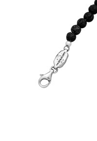 Black stone bead bracelet with a silver lobster clasp. Features a small white bead and a tag engraved with "Maze & Glory."