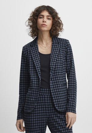 Blazer à carreaux noir et bleu avec des revers en pointe et des poches avant, ajustement sur mesure, fabriqué à partir d'un tissu lisse, associé à un haut noir.