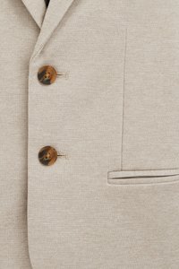 Bežinis švarkas su tekstūruotu audiniu. Turintis du rudus mygtukus ir vieną kišenę. Dizainą papildo žemyn nubrosta apykaklė ir subtili siuvinėjimo detalė.