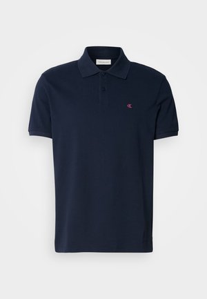 Donkerblauwe polo shirt van katoen met een klassieke kraag, korte mouwen en een klein roze logo op de linkerborst. Glad textuur.