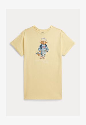 Hellgelbes T-Shirt mit einem aufgedruckten Bären, der einen Fischerhut, eine Jeansjacke, gestreifte Hose trägt und einen Korb mit Blumen hält.