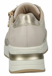 Beige athletic shoe featuring a golden metallic accent at the heel, textured fabric, and a zip closure on the side.