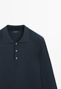 Polo a maglia blu navy con tre bottoni, dettagli a coste sulle spalle e colletto piatto. Realizzato in tessuto morbido.