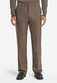 Bruna byxor i ett slätt, strukturerat tyg, med knappstängning och veck, tillsammans med svarta skor och en grå tröja.