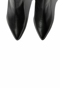 Zapatos de tacón negros de cuero con punta afilada, de textura suave y diseño minimalista. La suela presenta un acabado elegante; las sombras realzan la forma.