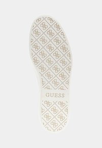 Soletta di scarpa bianca con un motivo a diamante ripetuto e un logo dorato con il nome del marchio "GUESS" al centro, texture liscia uniformemente.