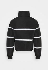 Svart puffjacka med hög krage och horisontella reflekterande vita ränder över ryggen och ärmarna, elastiska manschetter.