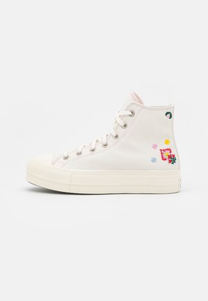 Baskets montantes blanches en toile avec lacets blancs et petite broderie florale colorée sur le côté extérieur près du talon.