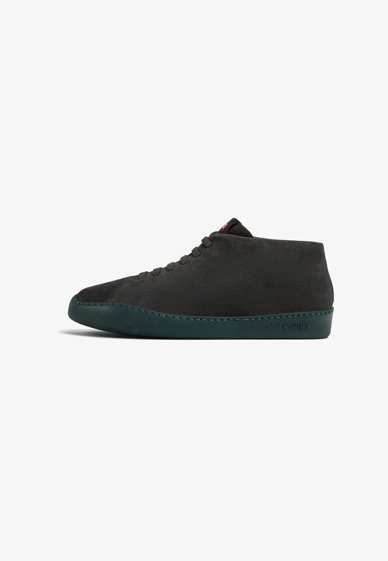 Black suede high-top shoe with a rounded toe, green rubber sole, and dark eyelets. Features a minimalistic design with subtle stitching detail.