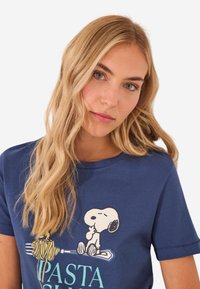 Navy blauwe katoenen t-shirt met een grafische afbeelding van Snoopy met pasta, ronde hals, korte mouwen en een ontspannen pasvorm.