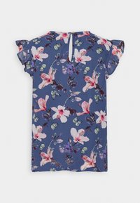 Blaue Bluse mit floralem Muster, die pinke und weiße Blumen sowie grüne Schmetterlinge zeigt, kurze voluminöse Ärmel hat und eine Schlüsselöffnung auf der Rückseite besitzt.
