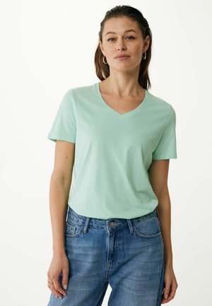 Mintgroen V-hals t-shirt gemaakt van zachte stof, korte mouwen, gecombineerd met lichtblauwe hooggetailleerde jeans. Eenvoudig ontwerp, geen zichtbare patronen.