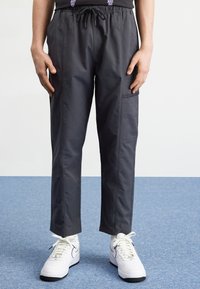 Gray, lightweight cargo pants with an elastic waistband, side pockets, and a tapered leg design. Styled with white athletic sneakers.