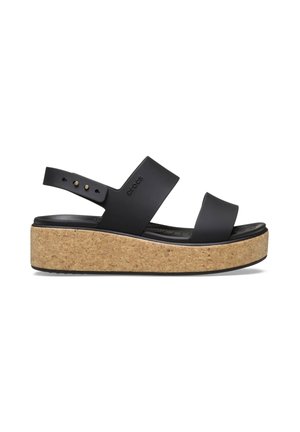 Black platform sandal with two wide straps and cork-textured sole, featuring a back strap with adjustable holes and studs.