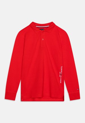 Rotes Langarm-Polohemd aus Baumwolle. Mit Kragen, zwei Knöpfen und seitlichen Schlitzen. "TOMMY HILFIGER" in Weiß auf dem Ärmel bedruckt.