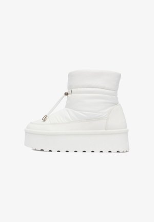 Bílé kotníkové boty s polstrovaným svrškem, elastickým zapínáním a silnou, strukturovanou platformou. Hladký materiál s lesklým povrchem.